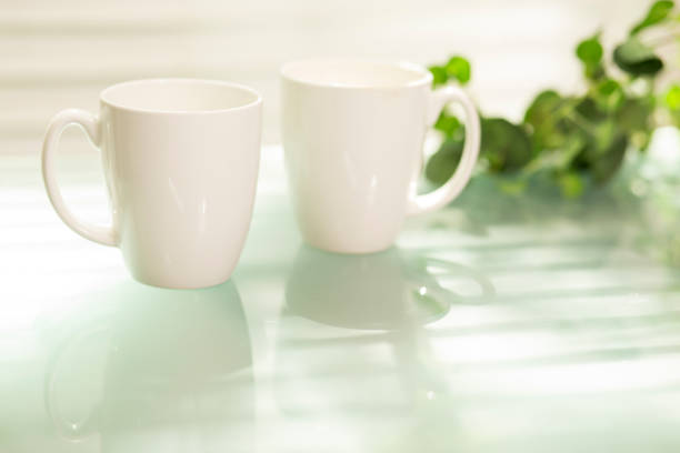 istock A pair of coffee mugs sit on glass top table. 1271624465