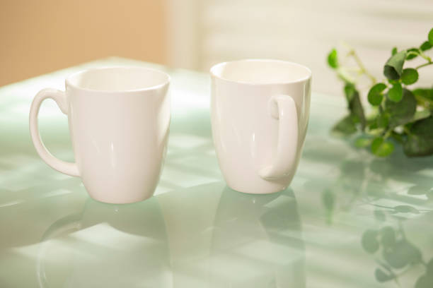 istock A pair of coffee mugs sit on glass top table. 1271624477