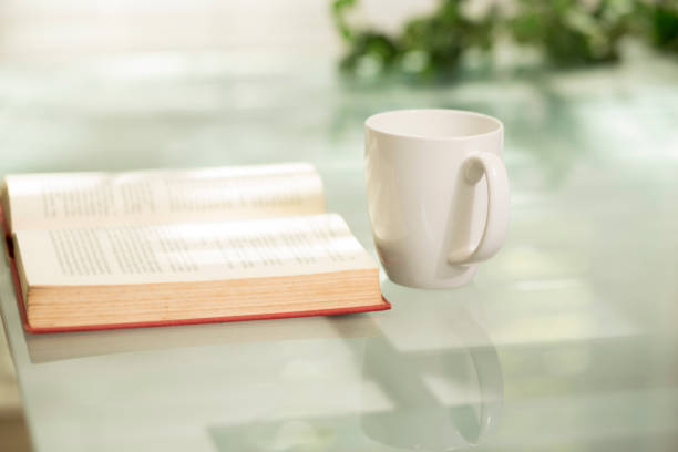 istock Open book and cup of coffee grace a glass top table. 1271624499