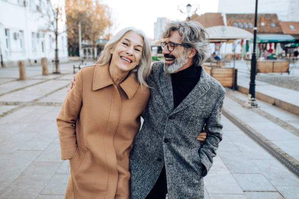 Happy senior couple in the walk Portrait of the mature man and woman walking down the street and enjoying together. street friends stock pictures, royalty-free photos & images