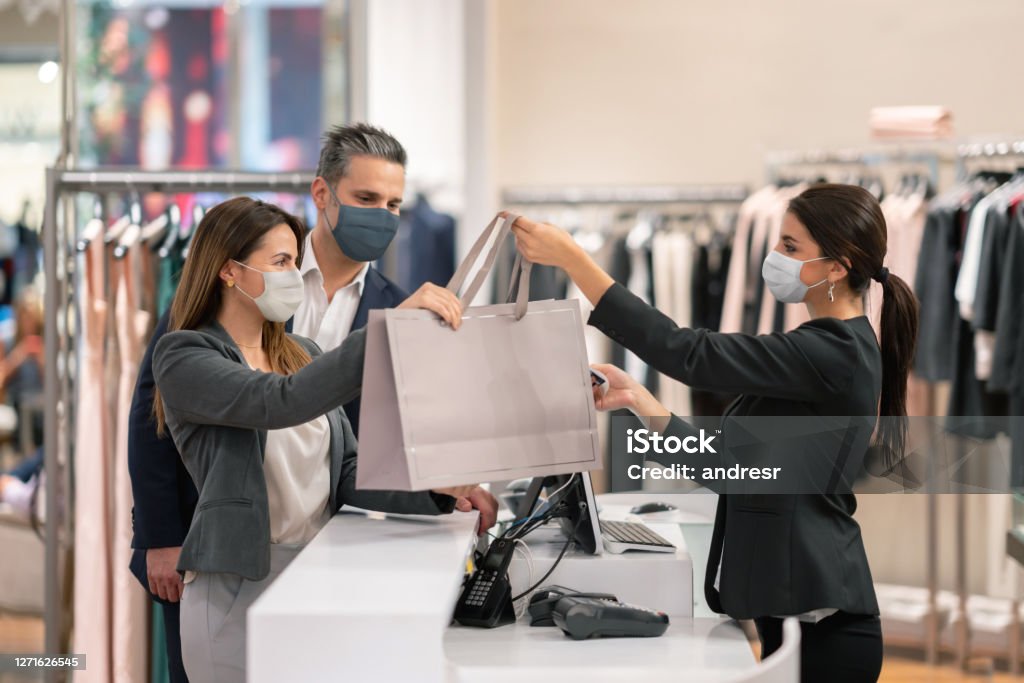 Couple shopping at a clothing store and using facemasks during the pandemic - Royalty-free Comércio - Consumismo Foto de stock