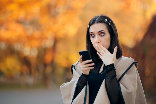 Woman checking her phone receiving shocking news