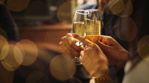 manos sosteniendo copas de vino o champán toasing y clinking juntos para celebrar la amistad - clunking fotografías e imágenes de stock