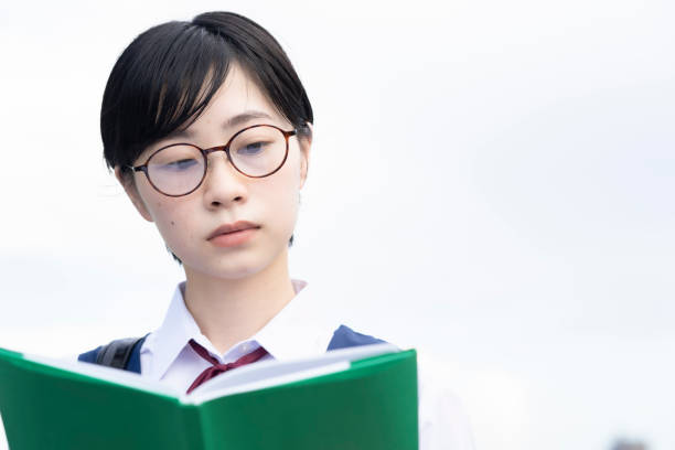 Asian schoolgirl wearing glasses and reading a book Asian school girl reading a book with a serious expression high school student photos stock pictures, royalty-free photos & images
