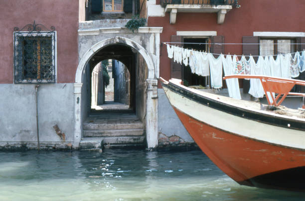 decaying building with steps to canal, alleyway, working boat, washing on clothesline, no people