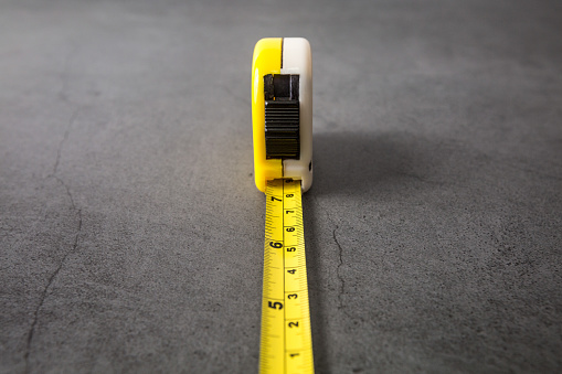 Selective focus of Yellow tape measure on concrete background and copy space