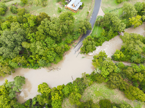Aerial view of flooded water flowing through river surrounded by houses in village.