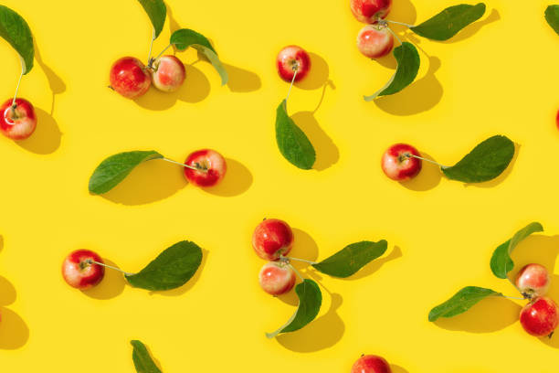 istock Seamless creative pattern from ripe small red apples and green leaves on yellow color background.  Food concept. Vegetable background. 1271642652