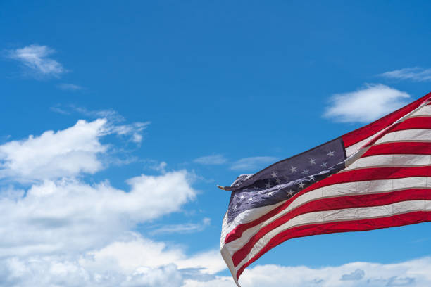 istock Waving USA flag under blue sky background. 1271650234