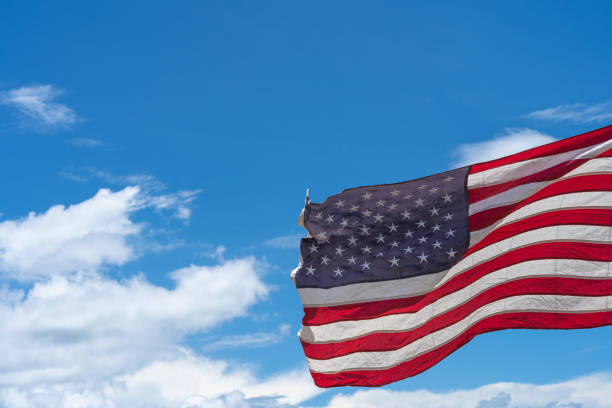 istock Waving USA flag under blue sky background. 1271650237