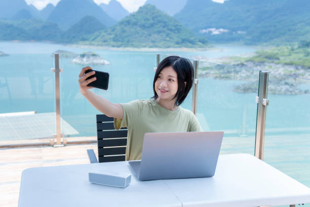 istock An Asian female freelancer using a laptop to work outdoors and making a video call with mobile phone in the journey 1271653506