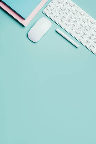 Home designer office workspace. White mouse, keyboard, notebook, pen on blue background. Top view. Copy space. Flat lay. Remote job, work. Feminine workspace. Blogger, business concept. Mock up