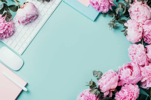 istock Home office workspace with white keyboard, notebook and peony, eucalyptus flower, copy space on blue background. Feminine workspace. Flat lay. Blogger, business concept. Mock up. Birthday, Woman day. 1271654576