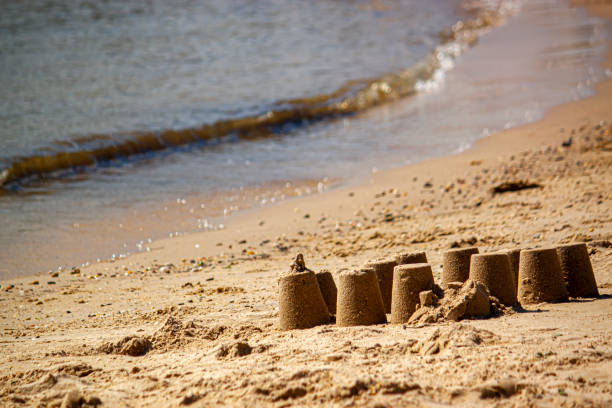 An abstract beach holiday themed image featuring a close up look to a sand castle made with wet sand on a beach.