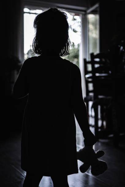 무서운 벽에 그녀의 손에 그녀의 헝겊 인형과 빛에 대한 어린 소녀. 할로윈 공포 개념 - baby doll dress 뉴스 사진 이미지