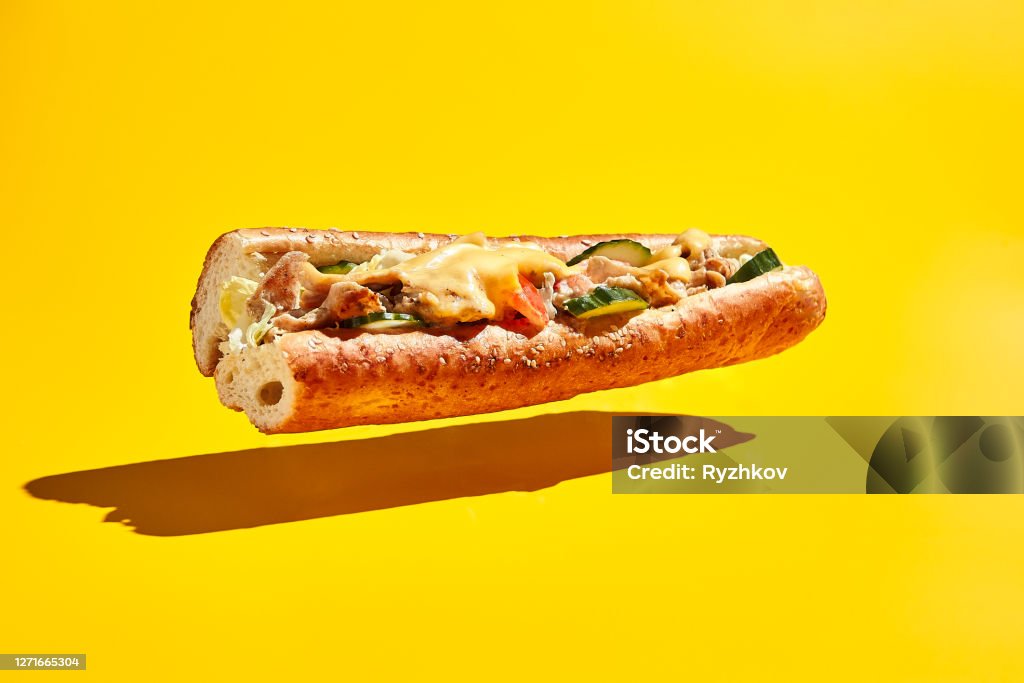 Flying chicken sandwich on yellow background American fast food minimal concept. Flying chicken sandwich on yellow background. Chicago cheese steak Sandwich Stock Photo