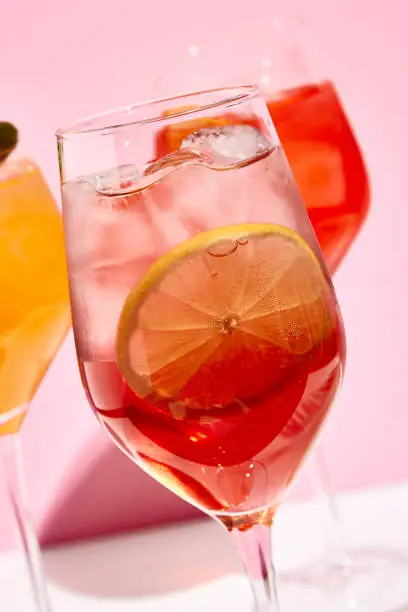 Raspberry spritz cocktail. Pink background. Cocktail with lemon slice and ice