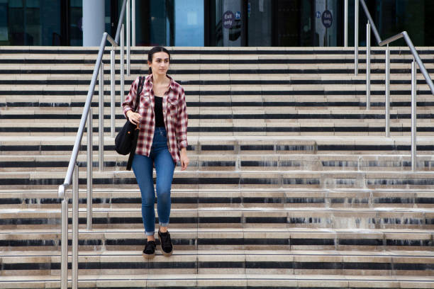 estudante do sexo feminino descendo degraus de um prédio universitário com espaço de cópia - staircase steps moving down student - fotografias e filmes do acervo