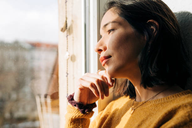 Contemplated female looking through window