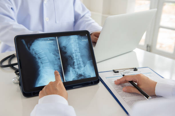 lumbar vertebrae x-ray lumbar vertebrae x-ray image by mri on digital tablet screen with medical team for consult. x ray pelvis stock pictures, royalty-free photos & images