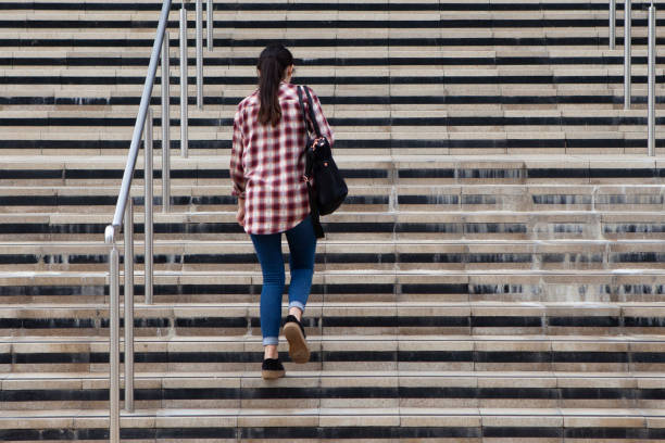 istock Female student walking up steps into a university building viewed from behind with copy space 1271666549
