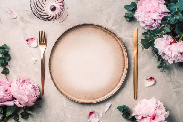 istock Tableware, flowers for serving a festive table, dinner. Stoneware plates, golden cutlery, eucalyptus branches, peony flowers on marble background. Copy space. Flat lay, top view. Table setting 1271666819