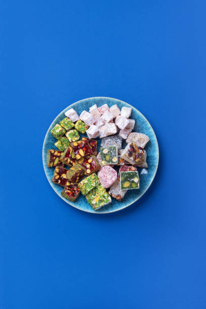 middle eastern sweets. turkish delight with pistachios nuts on plate over blue background. top view. copy space. arab dessert, rahat lokum, sherbet, nougat, churchkhela, cookies. flat lay. - turkey turkish culture middle eastern culture middle east imagens e fotografias de stock