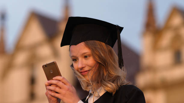 istock Young cute student graduate texting message on her phone 1271670972