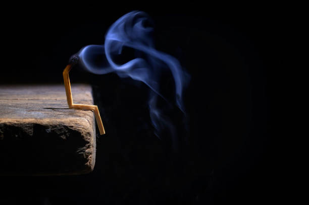Conceptual burned out and smoke wooden matches on black background stock photo
