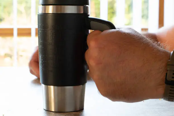 close up of male hands holding a coffee thermos mug