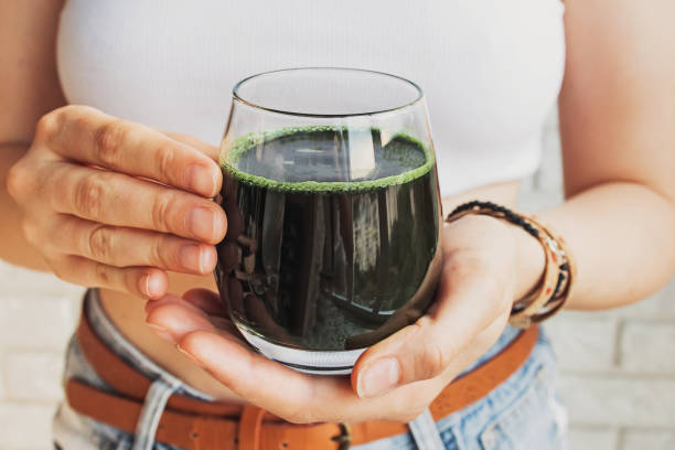 Woman holding glass with healthy spirulina drink close-up Woman holding glass with healthy spirulina drink or green smoothie close-up chlorella stock pictures, royalty-free photos & images