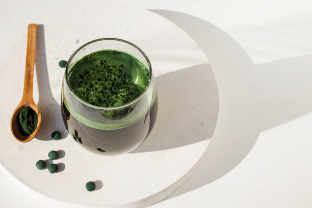 Spirulina or chlorella. Green food supplement. Spirulina or chlorella in a glass. Green food supplement, healhy lifestyle. Natural light and plant shadow on the table chlorella stock pictures, royalty-free photos & images