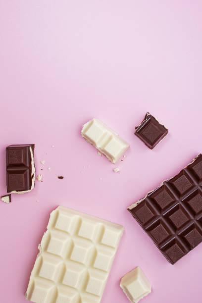 istock White and black chocolate bars and pieces on pink background, top view 1271678535