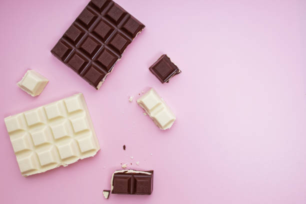 istock White and black chocolate bars and pieces on pink background, top view 1271678541