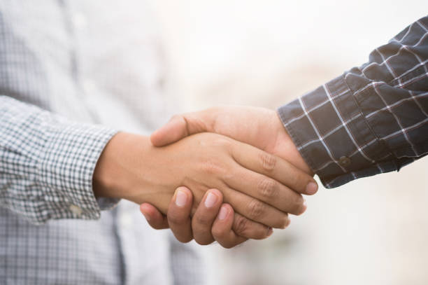 two men shaking hands to dealing success agreement business. business people wearing scott shirt on city view background. - team human hand cheerful close up imagens e fotografias de stock