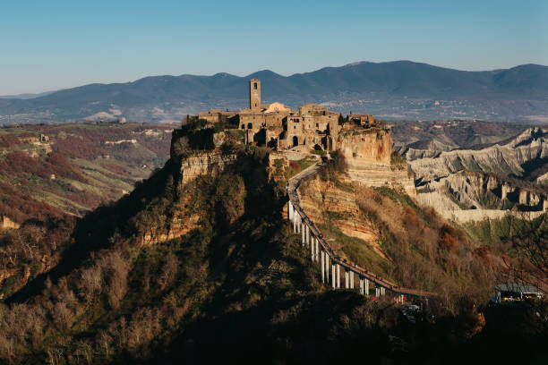 Civita di Bagnoregio - ancient hilltop village in Italy. Almost ruins, abandoned, travel destination. View from distance - with mountains panorama on winter day. stock photo