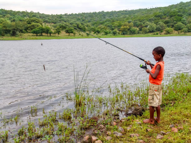 istock fisherman African kid catching a fish by the lake 1271680733