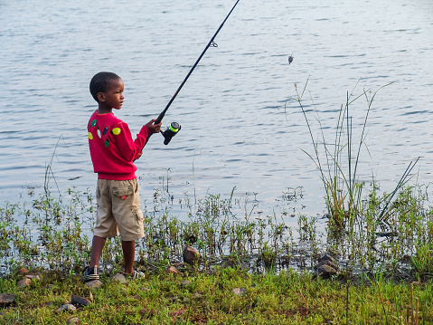 fisherman African kid catching a fish by the lake in the bush in Botswana