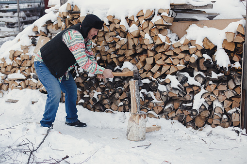 Man cutting firewood for the winter in the yard