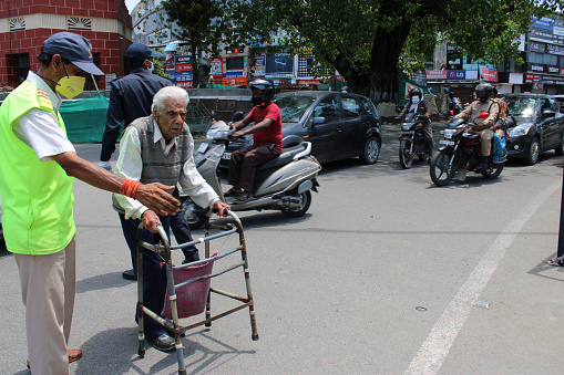 Dehradun, Uttarakhand/India - September 06 2020: An old man crossing the road with the help of a walker.