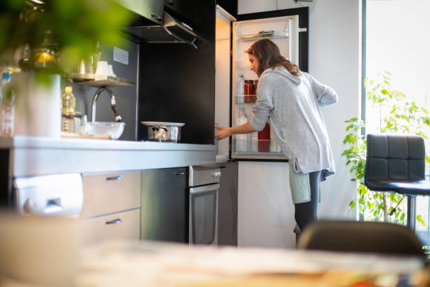 donna che apre il frigorifero per trovare gli ingredienti per il pranzo - frigorifero foto e immagini stock
