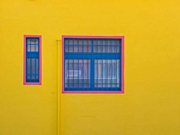 istock yellow facade of a house, with barred windows which have a red frame 1271686262