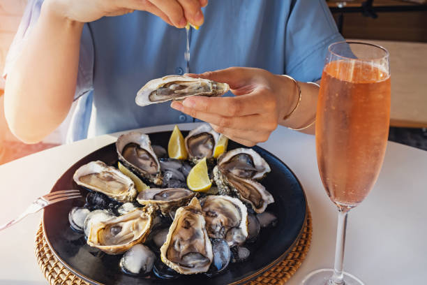 Woman eating fresh oysters with lemon close-up.