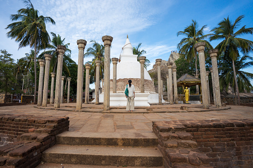 Mihintale / Sri Lanka - August 10, 2019: Young Asian tourist in front of Ambasthala Dagaba stupa with columns in Mihintale Buddhist temple