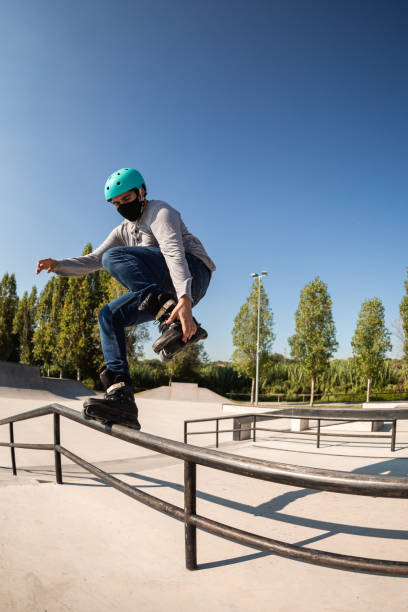 istock male roller skater with protective helmet and coronavirus prevention mask does a trick in a skate park 1271687529