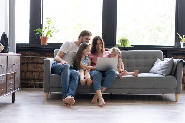 istock Smiling parents and kids using laptop on sofa at home, enjoying funny video at computer 1271688369