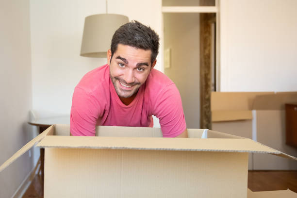 istock Cheerful young man unpacking things in his new apartment 1271689395