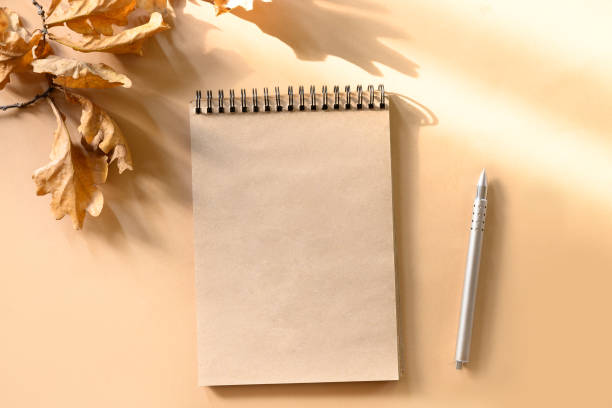 istock Autumn composition, scetchbook and golden dry oak leaves on beige with sunny shadow. Copy space. View from above. 1271689488