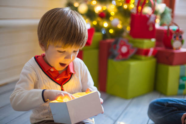 istock Surprised child opening and looking inside a magic gift over Christmas tree 1271691308