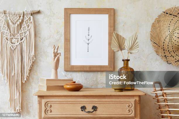 Stylish Boho Interior Of Living Room With Brown Mock Up Poster Frame Elegant Accessories Flowers In Vase Wooden Shelf And Hanging Rattan Hut Minimalistic Concept Of Home Decor Template Stock Photo - Download Image Now